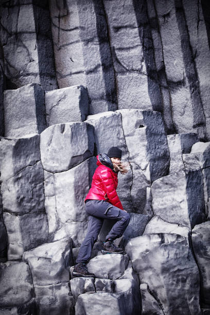 istock Woman climbing basalt columns at Reynisfjara beach 1170964788