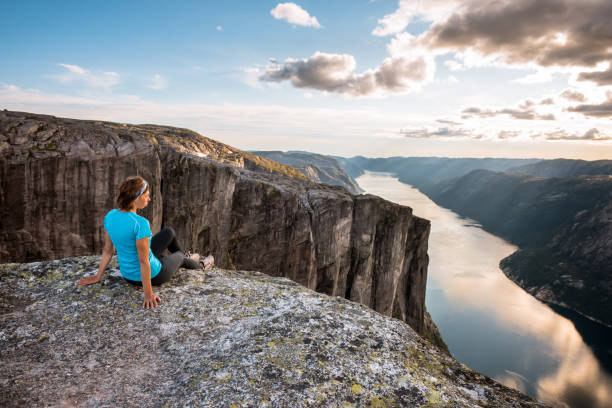 sportliche frau auf dem gipfel des fjords bei kjeragbolten, norwegen. - kjeragbolten stock-fotos und bilder