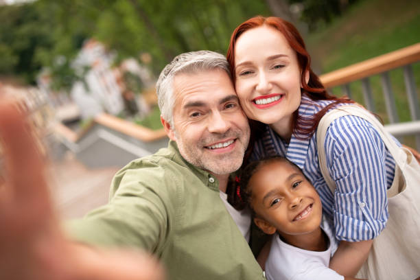 padres e hija sonriendo ampliamente mientras posan para la foto - pareja acogido al aire libre fotografías e imágenes de stock