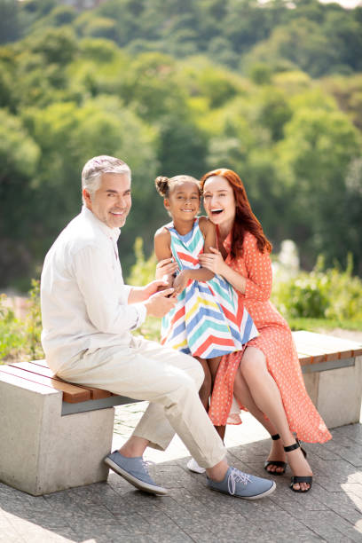 istock Adoptive parents hugging their cute little girl while walking together 1170968310