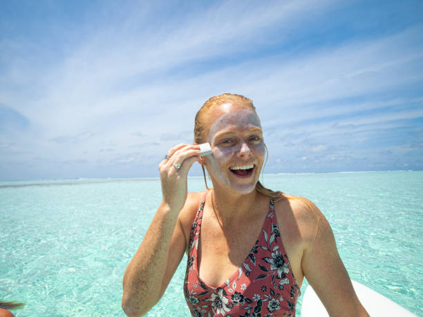 istock Woman Using Sun Lotion next to Paddle Board in Blue Ocean 1170969684