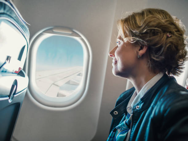 istock Woman looking through window in airplane 1170970895
