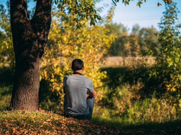 istock One man sitting by a tree in autumn Park 1170973076