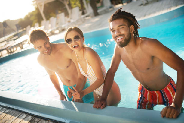 istock Dark-skinned beaming man standing near friends in the pool 1170978330