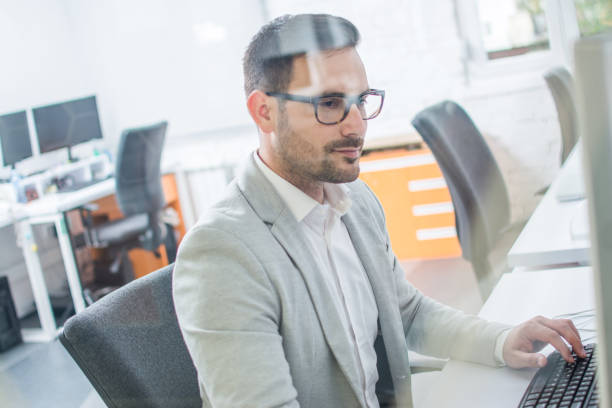 istock Confident and concentrated well-dressed businessman wearing eyeglasses using computer in office 1170978452