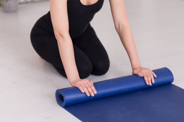 istock Young girl in training outfit rolling up the blue mat 1170982132
