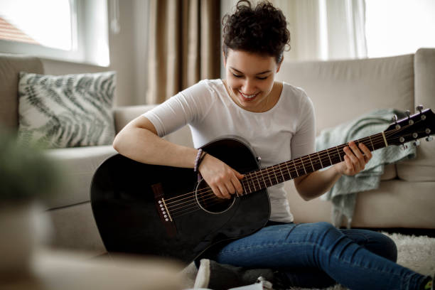 istock Relaxed woman playing a guitar at home 1170984016