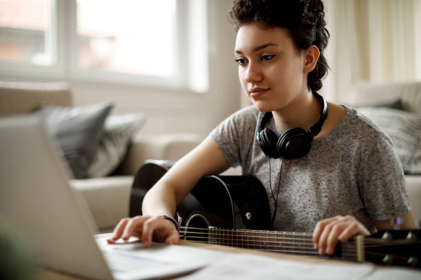 istock Smiling girl learning to play guitar at home 1170984018