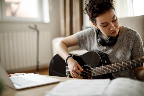istock Cute young woman playing a guitar at home 1170984046