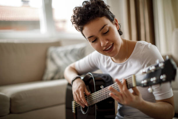 istock Smiling girl playing a guitar at home 1170984067