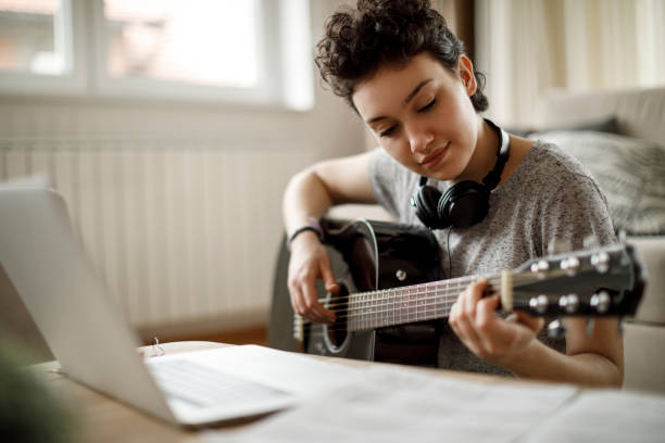 istock Young woman playing a guitar at home 1170984094