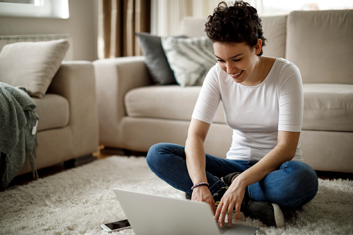 Smiling young woman working on laptop at home