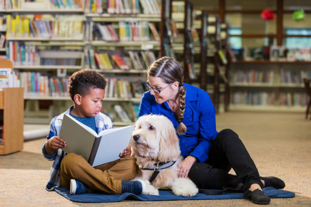 istock Mixed race boy reading in library with therapy dog 1170987851