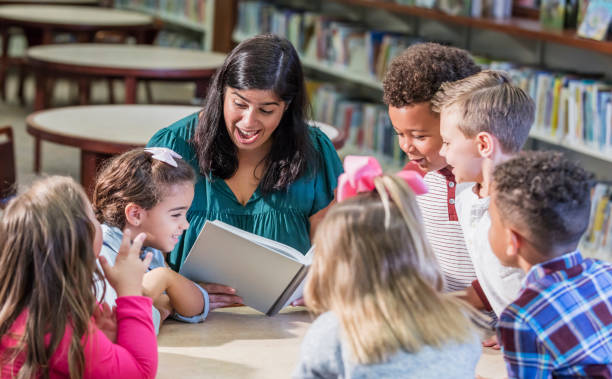 istock Hispanic teacher reading to children in library 1170988618