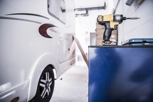 Camper Van RV Repair Concept. Recreational Vehicle in the Service Center. Drill Driver Power Tool.