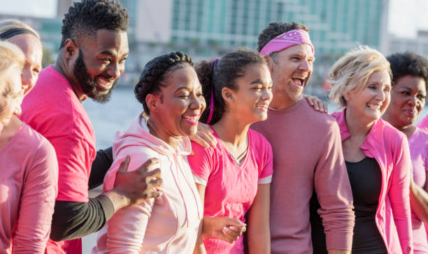 ピンクの男女のグループ,乳がんラリーで - side by side teamwork community togetherness ストックフォトと画像