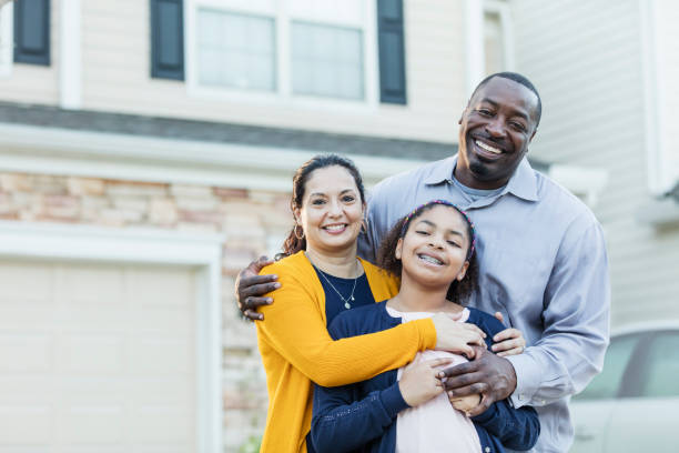 Mixed race African-American and Hispanic family An 11 year old mixed race Hispanic and African-American girl standing with her parents outside their home. Mom is a mature Hispanic woman and dad is a mature African-American man. They are both in their 40s, happy and proud of their daughter.  All are smiling at the camera. in front of photos stock pictures, royalty-free photos & images