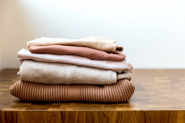 istock Stack of beige tones clothes on the wooden table. The order in a wardrobe, basic or capsule. 1170997788