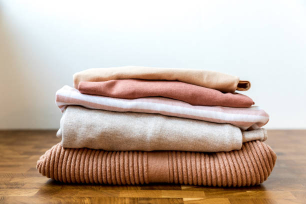 istock Stack of beige tones clothes on the wooden table. The order in a wardrobe, basic or capsule. 1170997802