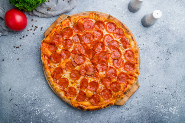 istock Pepperoni pizza on board on beautiful grey table 1170998046