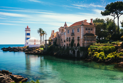 View of Santa Marta lighthouse and Municipal museum of Cascais, Portugal with bright green water from a stream flowing into the Atlantic ocean