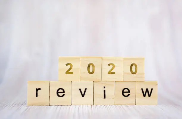 Photo of The word review on wooden cube block on white wooden table. 2020 review concept