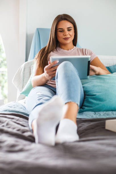 istock Happy young woman using digital tablet while relaxing in bed 1171009709