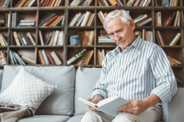 istock Senior man at home retirement concept sitting reading book 1171009905