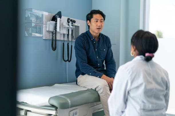 koreanischer mann in absprache mit arzt - asian ethnicity doctor patient healthcare and medicine stock-fotos und bilder