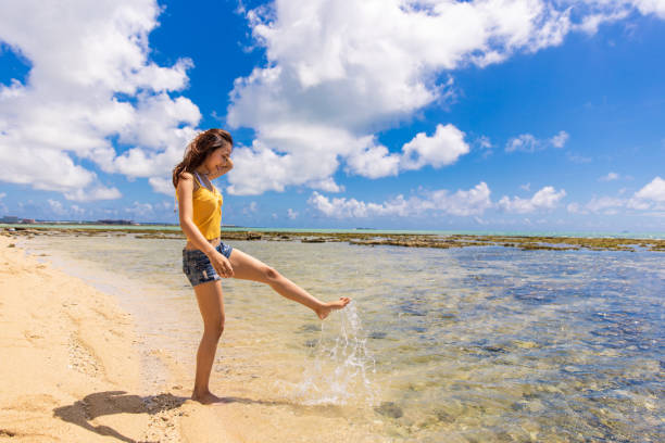 Young woman kicking water at summer beach