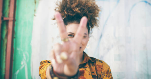 Give the world your peace Shot of an attractive young woman making a peace gesture in an urban setting peace sign gesture photos stock pictures, royalty-free photos & images
