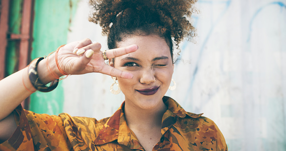 Shot of an attractive young woman making a peace gesture in an urban setting