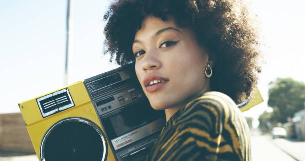 Shot of an attractive young woman listening to music on a boombox in an urban setting
