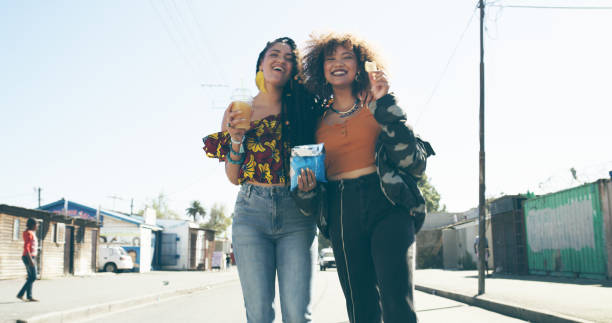 Who needs a mister when you've got ya sister? Shot of two attractive young women enjoying snacks in an urban setting family eating potato chips stock pictures, royalty-free photos & images