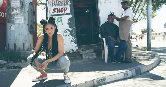 Shot of an attractive young woman crouching on a sidewalk in an urban setting