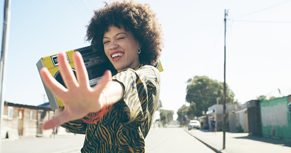 Shot of an attractive young woman listening to music on a boombox in an urban setting