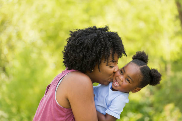 African American mother laughing and hugging her daughter. African American mother parenting his daughter. natural hair stock pictures, royalty-free photos & images