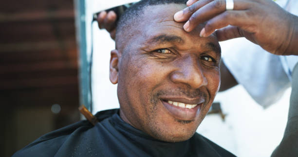 Expert service right down to the root Portrait of a mature man getting his hair cut outside in a small town black barber stock pictures, royalty-free photos & images