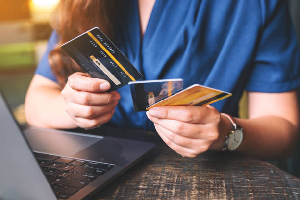 istock a woman holding and choosing credit cards while using laptop computer 1171034811