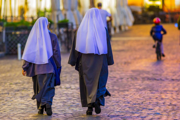 The world heritage city of Rome in Italy The historic city of Rome in the Italian province of Lazio on November 07, 2013: Nuns walking down the cobbled streets of the Centro Storico area of Rome Italy nun catholicism sister praying stock pictures, royalty-free photos & images