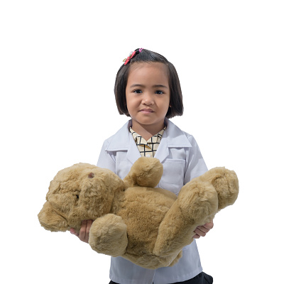 Cute Little asian girl doctor smiling while wearing Doctor's uniform Carrying a teddy bear. Standing isolated on white background with clipping path