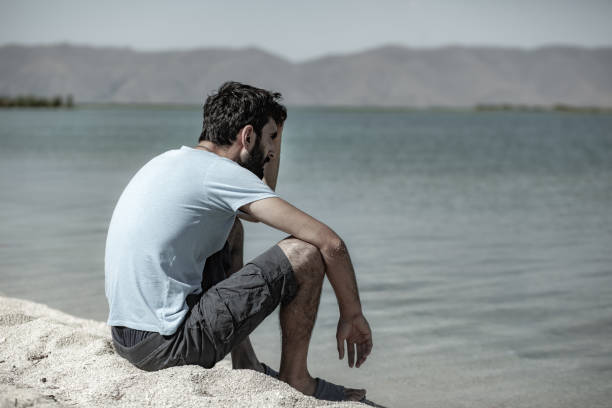 istock young man sitting on the shore 1171045224