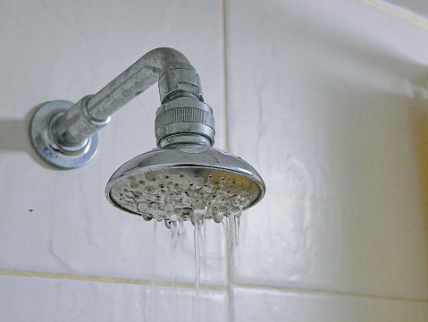 Primer plano de un cabezal de ducha parcialmente obstruido en un baño, haciendo que ponga tan poca agua photo