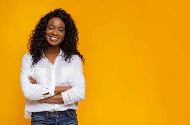 zelfverzekerde glimlachend afrikaans amerikaans meisje met gekruiste handen op de borst - woman smiling stockfoto's en -beelden