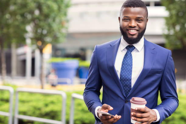 istock Cheerful african employee having coffee break and using smartphone outdoors 1171061532