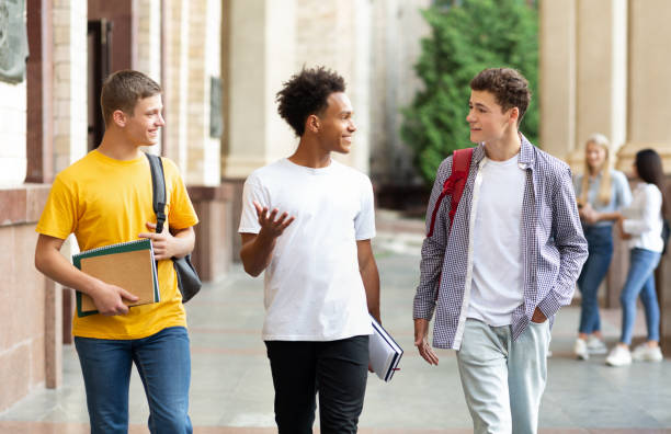 istock University life. Guys walking in campus and chatting 1171061801