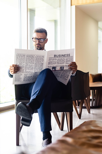 handsome businessman in suit and glasses reading newspaper business