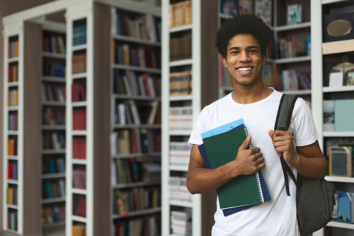 Handsome african american male student posing in campus library, empty space