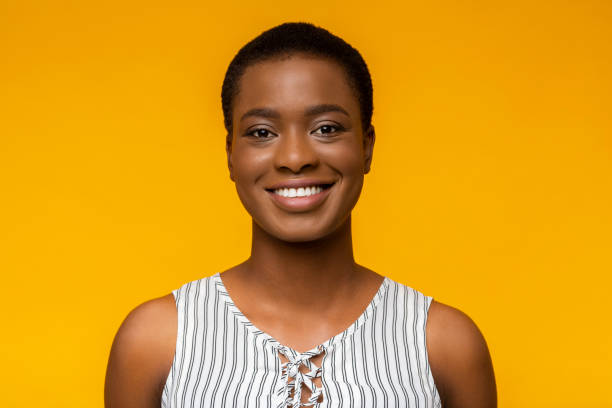 portrait of smiling black woman on yellow background - sensuality horizontal indoors studio shot imagens e fotografias de stock