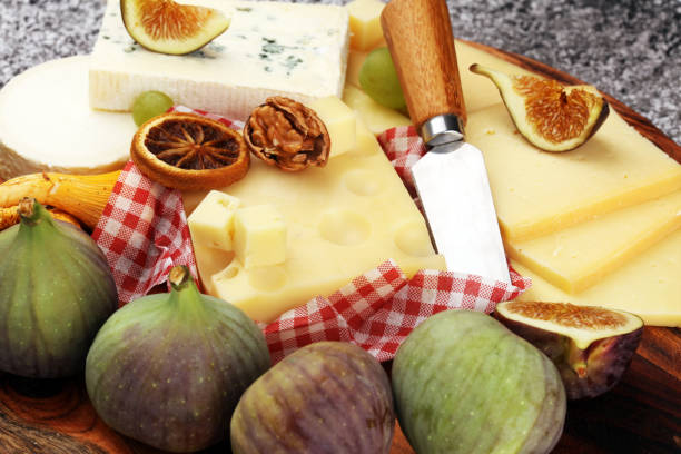 Cheese platter with different cheese and grapes and figs and nuts.